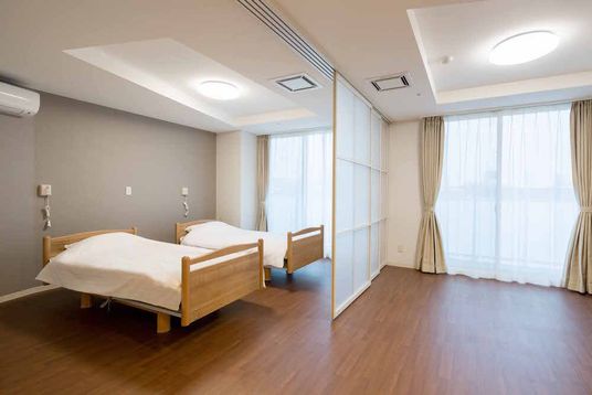 二つのベッドが左側に設置され、それぞれに緊急通報装置も付いている。右側のリビングスペースには家具は置かれていない。