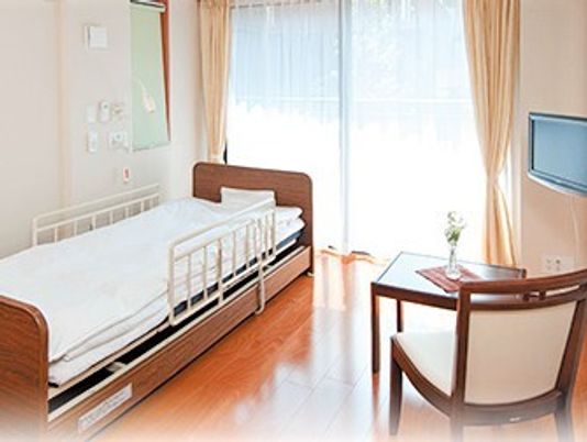 一人用のベッド、いす、テレビなどが置いてある個室仕様の部屋の様子。フローリング仕様の部屋