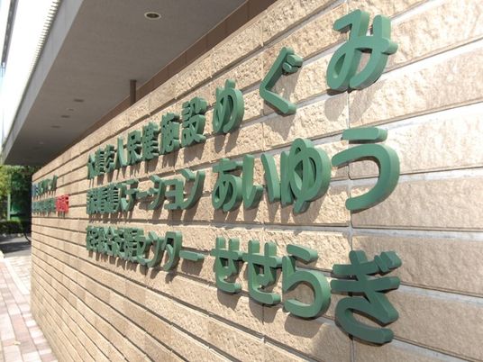 看板。文字色は緑、壁は薄茶のレンガ