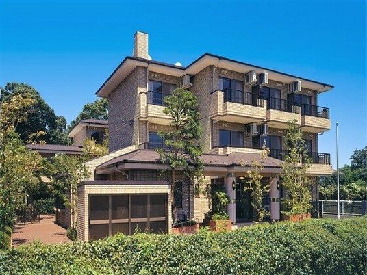 緑に囲まれた３階建ての建物はアットホームな雰囲気で、各フロアにベランダがあり、煙突も付いている。