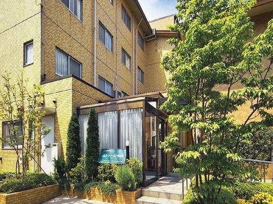 寝具付きのベッドやいすが置かれた居室にはフロアカーペットが敷かれ、大きな窓が付き明るい雰囲気。