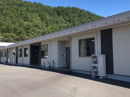 平屋建ての建物は横に長く、日当たりのいい場所に建っている。周りには緑が多い。