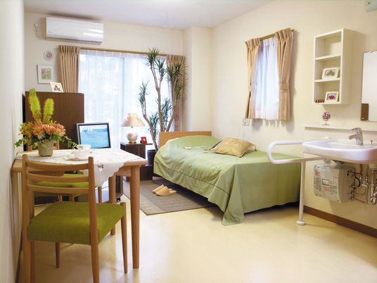 ベッドやエアコン、洗面所が設置された居室にはテレビやテーブルセットも置かれている。