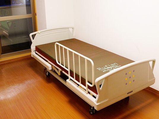 介護用ベッドがひとつだけ置いてある施設内の個室の様子。窓がある小さなワンルーム