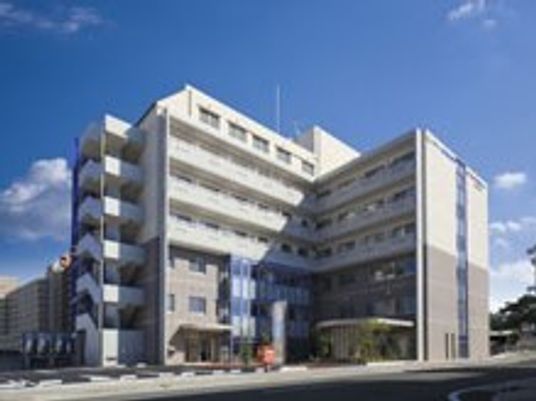青い空の下にある7階建ての大きな建物は白とグレーでまとめられ、スタイリッシュな外観。