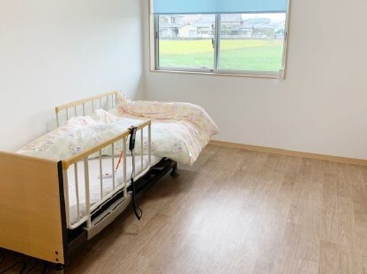 フローリングのフロアの個室の部屋には寝具付きのベッド屋窓があり、ベッドにはナースコールが付いている。