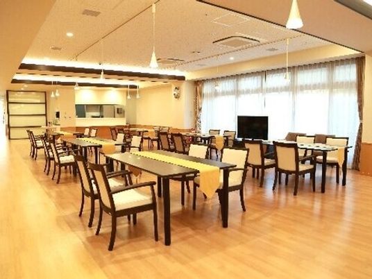 ダイニングテーブルが並んだ食堂は天井が高く、大きな窓が付き、テレビも設置され明るい雰囲気。