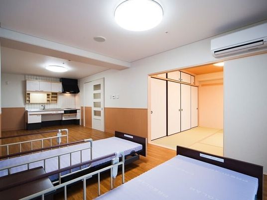 ベッドが2台置かれたフローリングの部屋の奥にはキッチンがあり、畳敷きの和室もある。