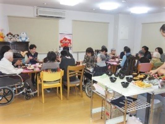 テーブルを囲んで食事を楽しむ入居者。車いすを利用している人も一緒に食べている。