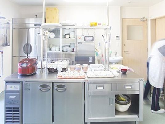 広めのキッチンのような場所に冷蔵庫と炊飯器などが置いてある様子