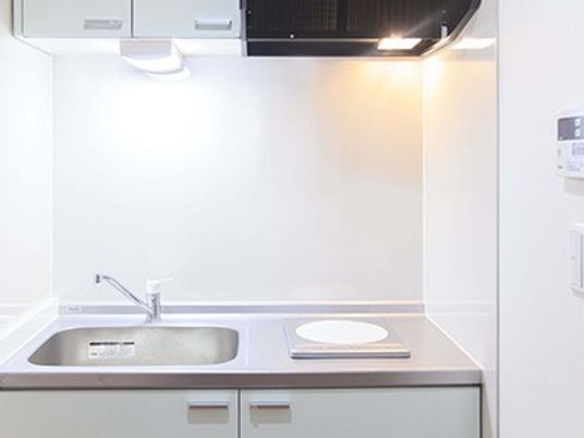 一人用らしき小さなキッチン。真紅と小さな電気調理器が写っている