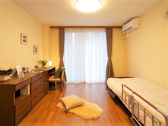 右側にエアコン、左側に濃い色合いのタンスが置いてある小さな部屋の様子
