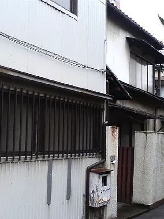 白い壁の一軒家風建物の外観。施設の外側から写した写真