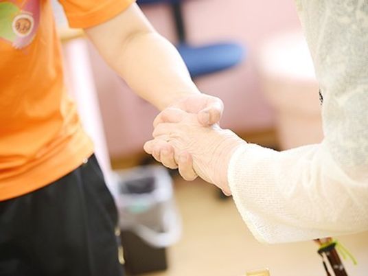 デイサービスでリハビリしている高齢者とスタッフの様子。手元を写した写真