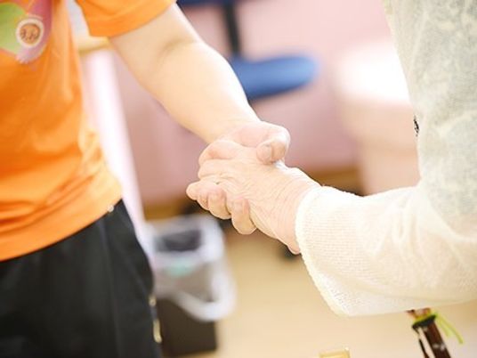 デイサービスでリハビリしている高齢者とスタッフの様子。手元を写した写真