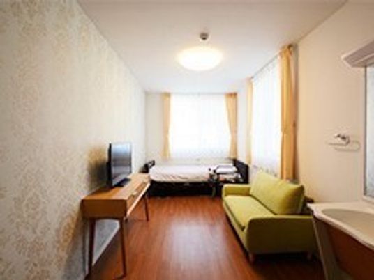ひとりで使う小さ目の部屋の様子。奥のほうにベッド、手前にテーブル、ソファ、洗面台がある