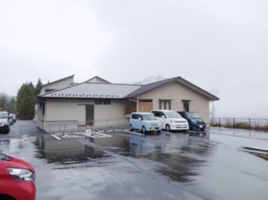 平屋建ての一軒家風の建物と、その周りに広がる駐車場