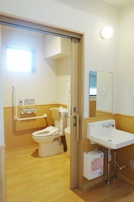 手すりが付いたトイレとすぐそばにある洗面台が写った写真