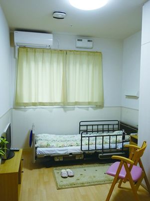 エアコン、ベッド、テレビ、いすなどが写っている小さな部屋