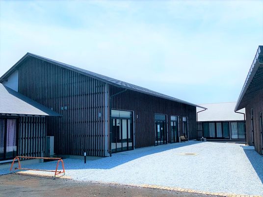 木造の建物は平屋建てで重厚感のある外観。三角屋根が付き、コの字型の建物の中央には庭のような広いスペースがある。