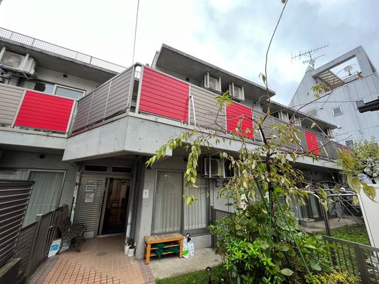 ベランダが付いた2階建ての建物の前には緑が植えられた庭があり、洗濯物干し場も設置されている。
