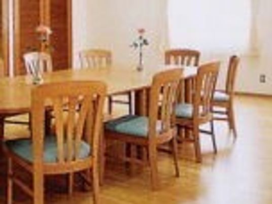 木製のダイニングテーブルセットが置かれている明るい雰囲気の食堂。テーブルの上には花も飾られている。