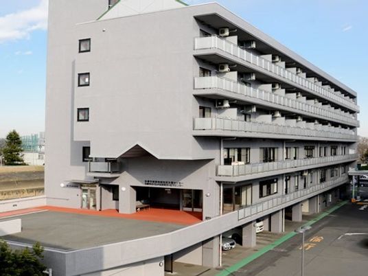 グレーの6階建ての建物はどっしりとしていて、1階部分が駐車場となっている。周りには背の高い建物はない。