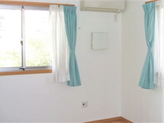 白い壁にフローリング、家具などは置かれていないが、エアコンが設置されたシンプルな居室。