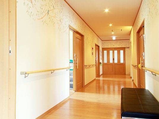 長く続く廊下に手すりとソファがある様子。施設内の廊下の様子