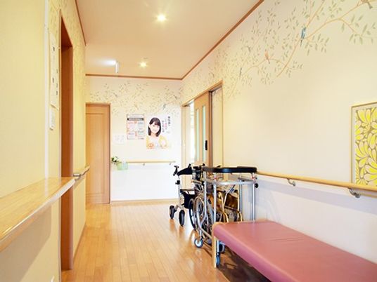 手すり付きの環境の廊下の様子。歩行訓練器具、車いすなどが置いてあるのが見える