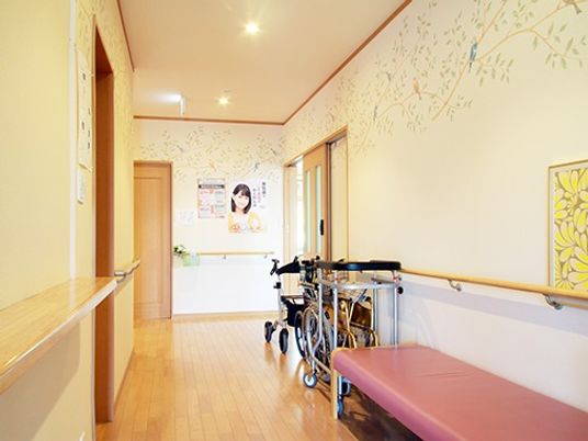 手すり付きの環境の廊下の様子。歩行訓練器具、車いすなどが置いてあるのが見える