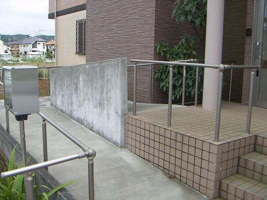 手すり付きのスロープや階段が設置された玄関にはシルバーの郵便ポストも設置されている。