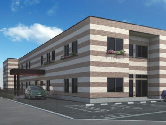 ストライプの外壁がスタイリッシュな雰囲気。駐車場が付いた２階建ての建物は玄関に車寄せが付いている。