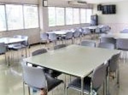 四角い机と椅子のセットがいくつか並んでいる施設内の共有スペースの様子