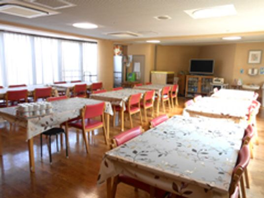 長机と椅子が複数組並んでいる施設内の共有スペース。日当たりの良い場所の様子