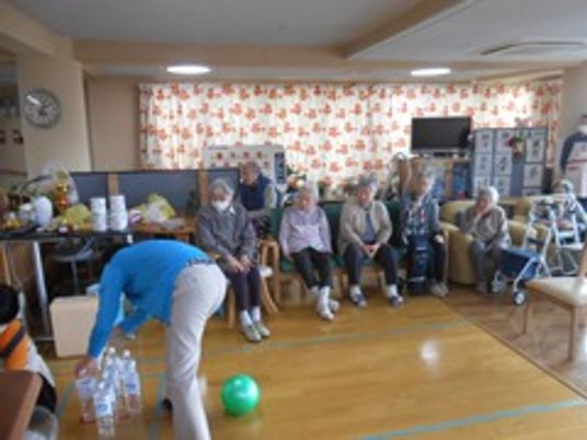 施設内でボーリング協議を楽しんでいる高齢者とそれを見つめている様子