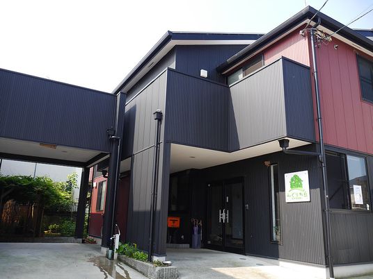 ２階建ての建物はネイビーを基調とし落ち着いた雰囲気。２階にはバルコニーもある。