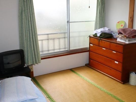畳敷きの居室にはタンスやベッドが置かれ、大きな窓も付いている。