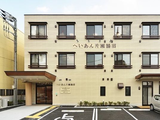 鉄骨造３階建ての建物の外観。駐車場が手前にあるマンションのような外観