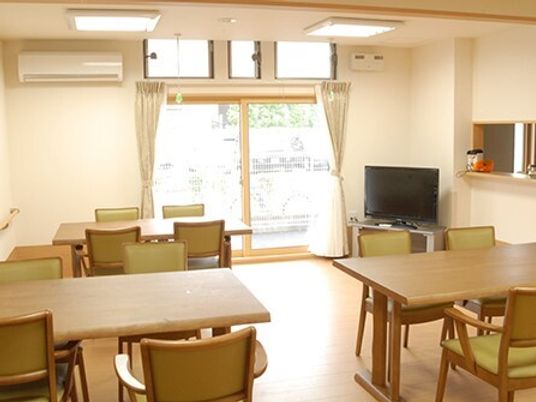 エアコン付きのリビングダイニングにはダイニングテーブルセットが複数あり、テレビも置かれている。