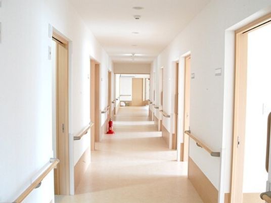 まっすぐな廊下の両サイドに居室のドアと手すりがあり、消火器も設置されている。