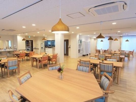施設内のリビングスペース。四人掛け・六人掛けのテーブルが並んでいる様子