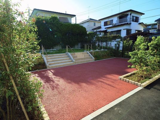 屋外にあるリハビリスペース。白く縁どられた赤いスペースと、階段が二つ付いている。