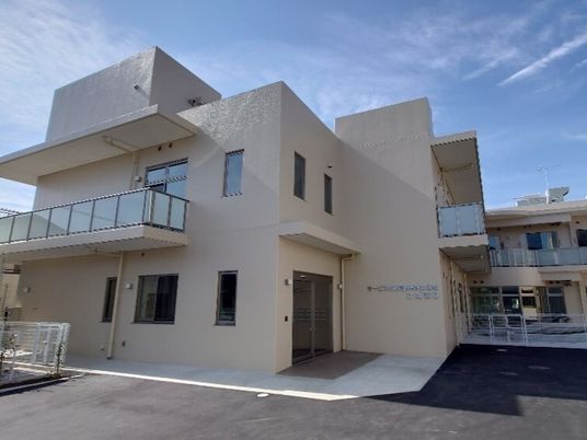 白を基調とした２階建ての建物は日当たり良好で玄関先には屋根があり、マットが敷かれている。