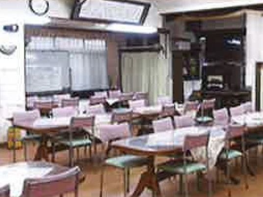 長テーブルが複数並んだ食堂。向かい合わせで椅子がセットされている。