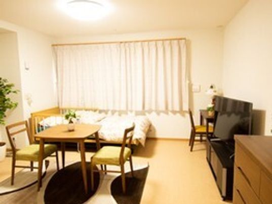 寝具付きのベッドやタンス、テーブルセット、デスクセットが置かれた部屋にはカーテンが付いている。