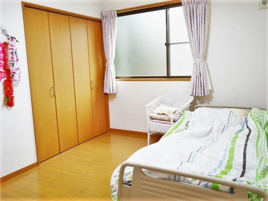 ベッドや収納、窓などが設置された居室はフローリングで椅子などの家具も持ち込まれている。