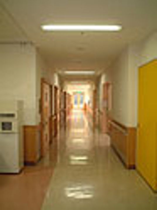 長く続く廊下の様子。オールバリアフリーの床と両側にある個室のドアが写っている