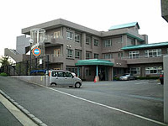 駐車場スペースが手前に広がる広い敷地とその奥にある建物の写真