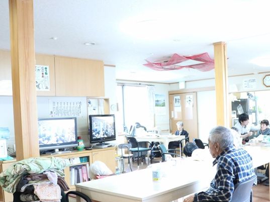 リビングダイニングは広く、テレビが２台とダイニングテーブルなどが置かれている。